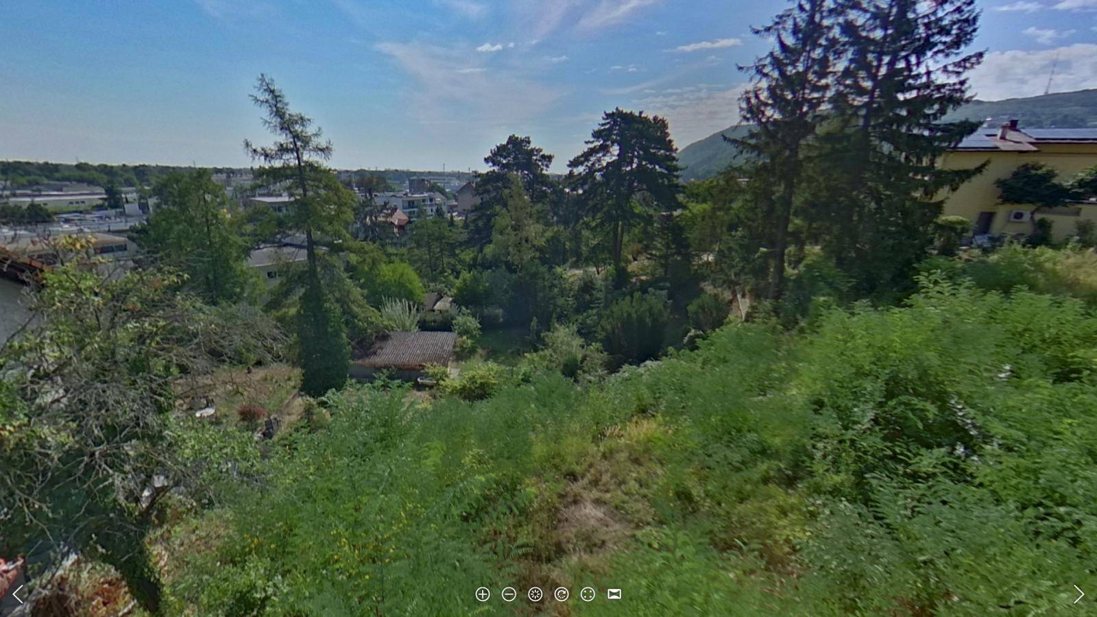 Weitläufiger Blick über eine bewaldete Landschaft mit vereinzelten Häusern und einem klaren Himmel.