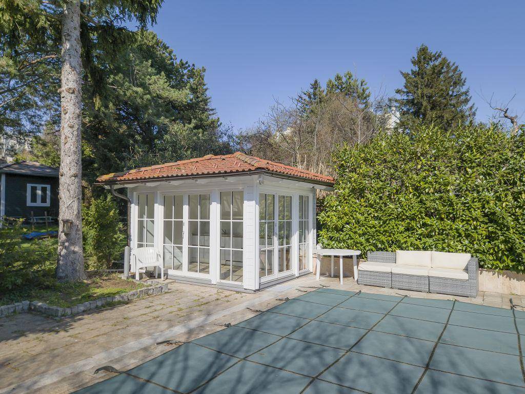 Gepflegter Gartenbereich mit einem charmanten Gartenhaus, abgedecktem Pool und Sitzgelegenheiten.