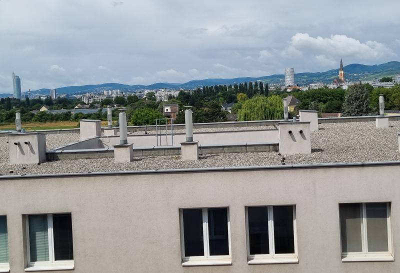 Mehrstöckiges Wohngebäude mit zahlreichen Fenstern und Parkplätzen an der Straße.
