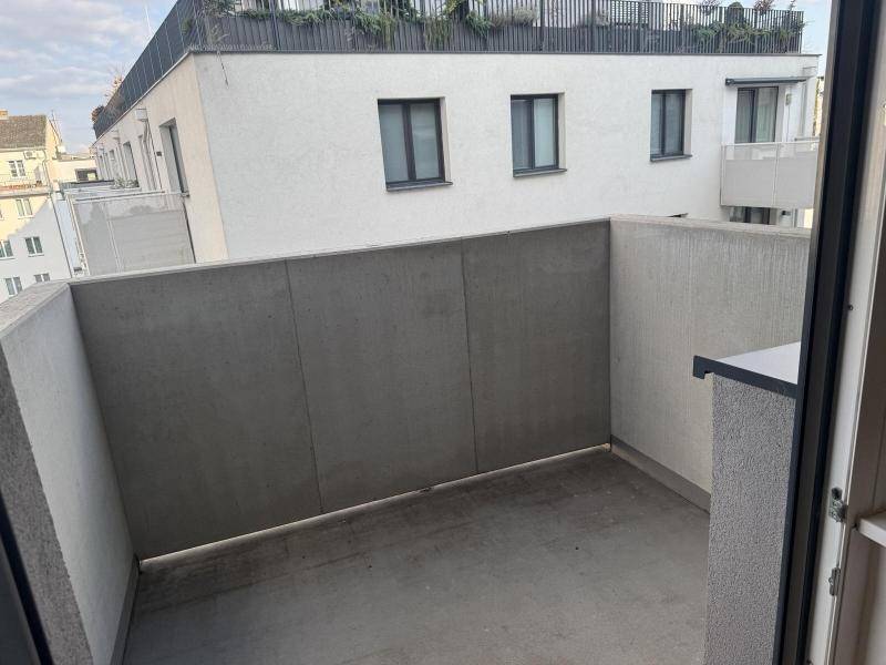 Moderne Einbauküche mit weißen Schränken, dunkler Arbeitsplatte und integrierten Küchengeräten.