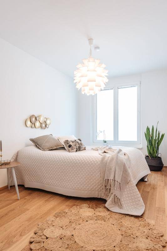 Helles Schlafzimmer mit Holzboden, großen Fenstern und minimalistischer, moderner Einrichtung.