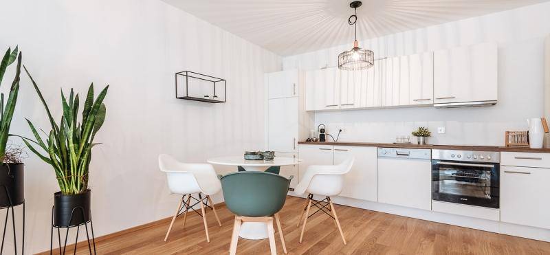 Helle, offene Wohnküche mit weißen Schränken, Holzboden und modernem Essbereich.