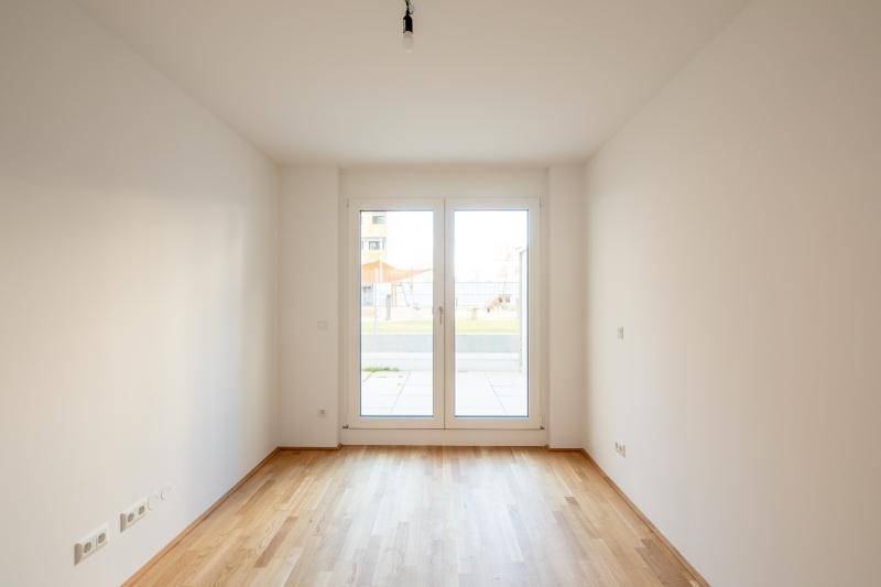 Geräumiges Zimmer mit viel Tageslicht, Holzboden und direktem Zugang zur Terrasse.