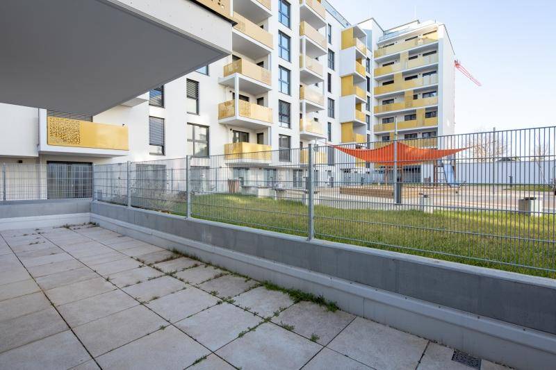 Terrasse mit Blick auf eine grüne Rasenfläche und den gemeinschaftlichen Kinderspielplatz.