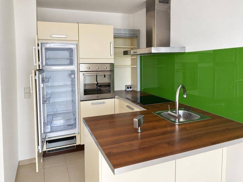 Moderne Küche mit beigen Schränken, grüner Rückwand und integrierten Geräten.