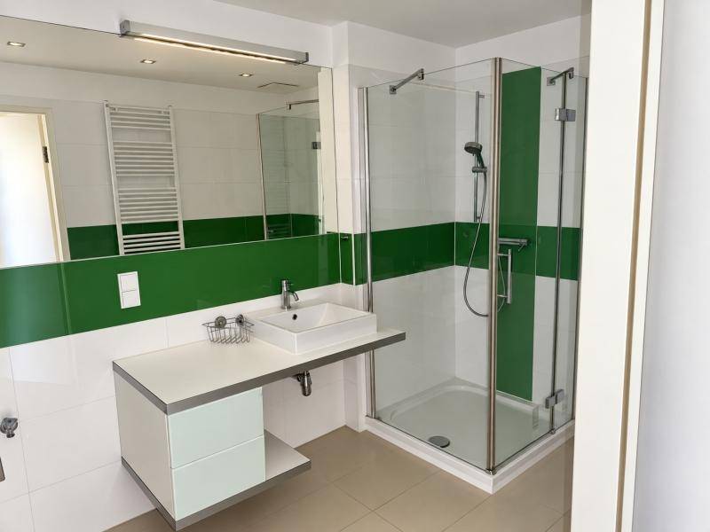Modernes Badezimmer mit Dusche, Einzelwaschbecken und grünen Akzentfliesen.