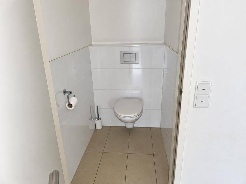 Kleines Gäste-WC mit wandhängender Toilette und weißen Fliesen.