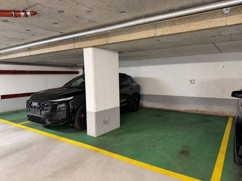 Tiefgarage mit markiertem Stellplatz und einem geparkten schwarzen Auto.