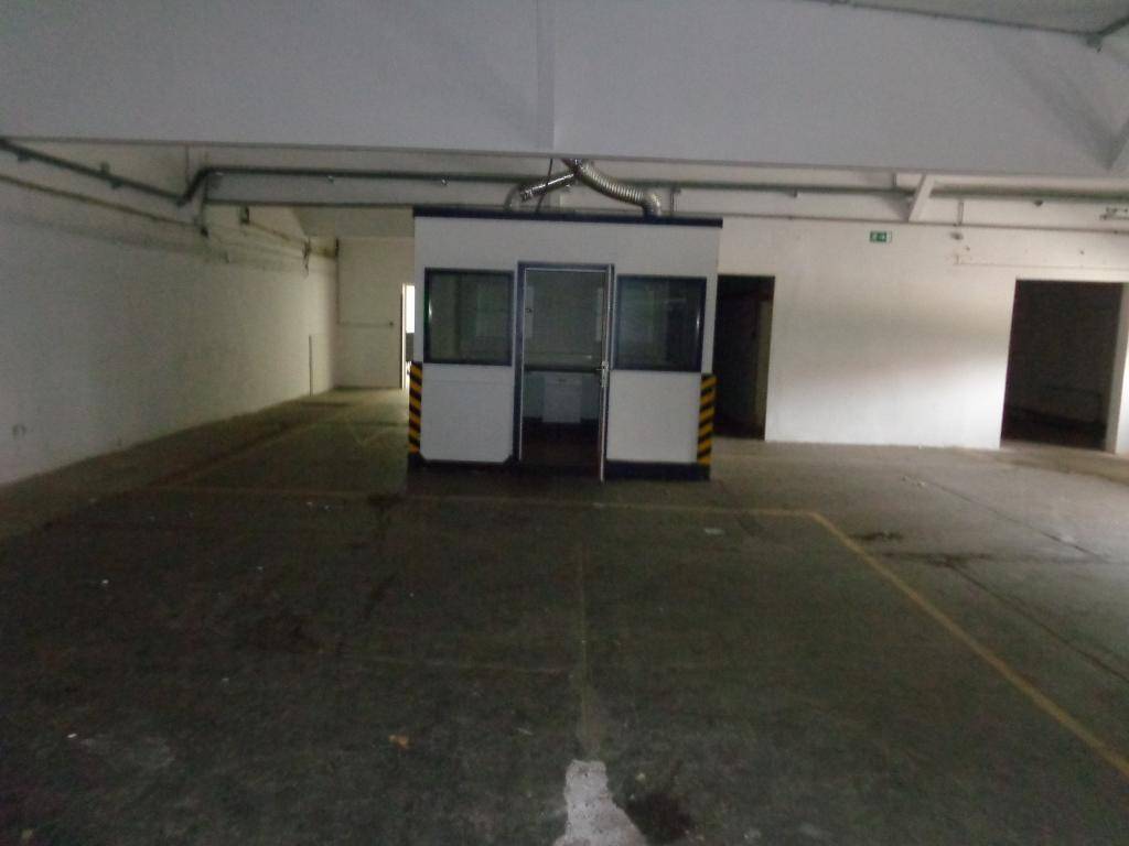 Große Lagerhalle mit einem freistehenden Büro- oder Wachhäuschen in der Mitte des Raumes.