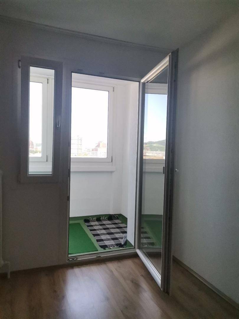 Balkonzugang vom Wohnzimmer mit großen Fenstern, die viel Tageslicht hereinlassen und Ausblick bieten.