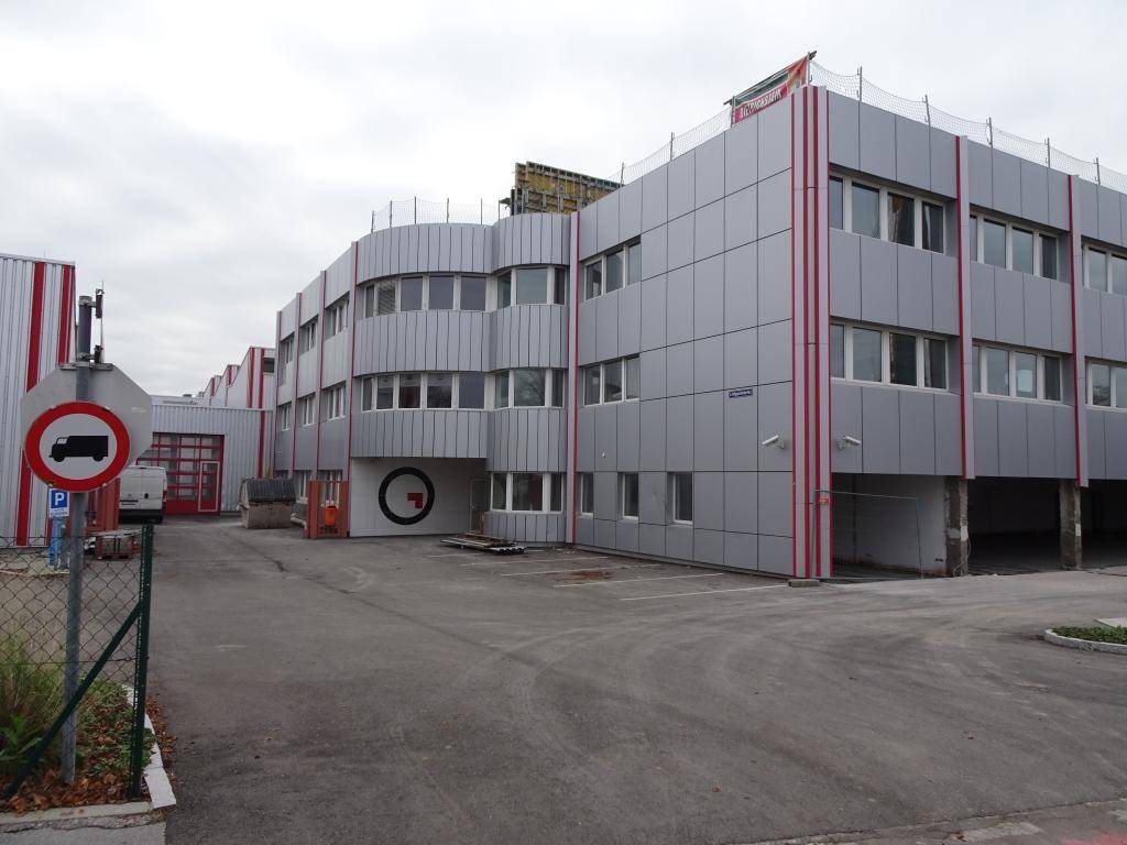 Moderne Fassade eines Gewerbegebäudes mit Metallverkleidung und roten Akzenten.