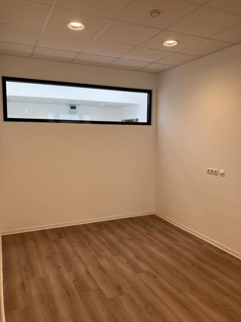 Kleines Büro mit Laminatboden und einem schmalen Fenster, das Tageslicht spendet.