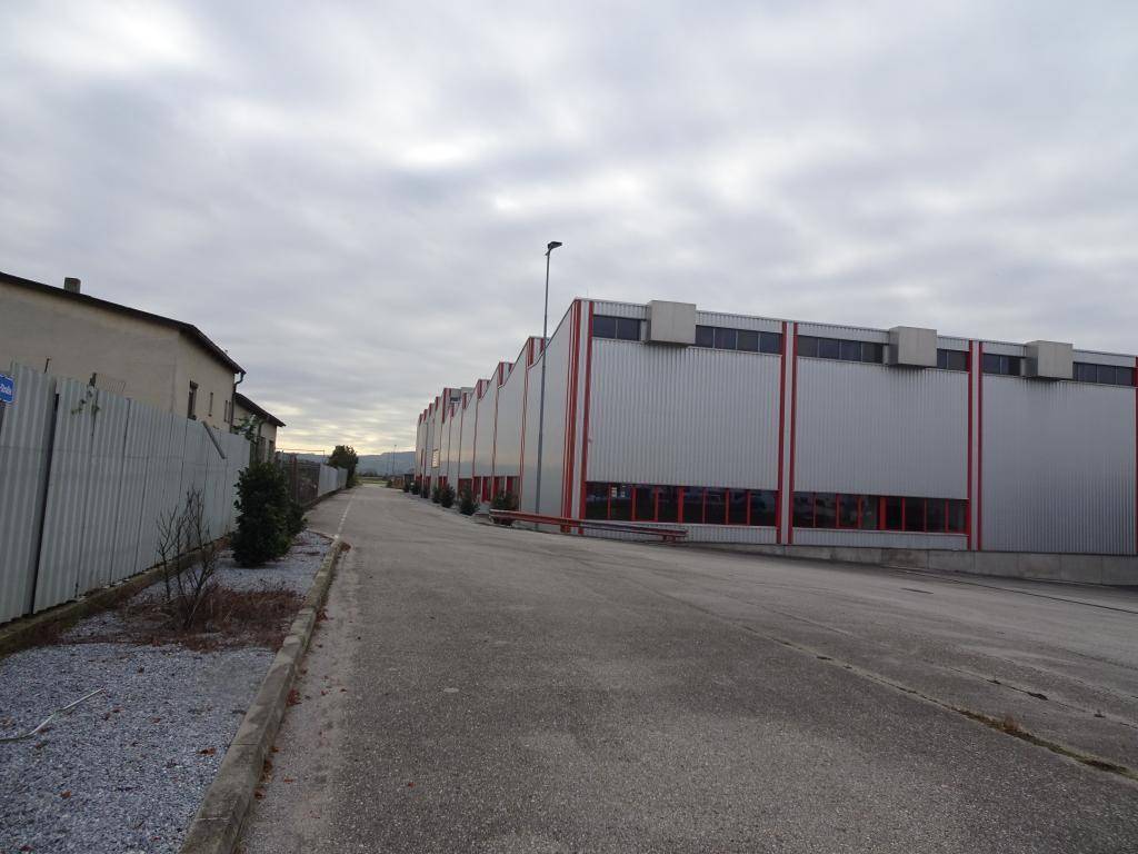 Lange Fassade eines Gewerbegebäudes mit roten Akzenten und Zufahrtsstraße.