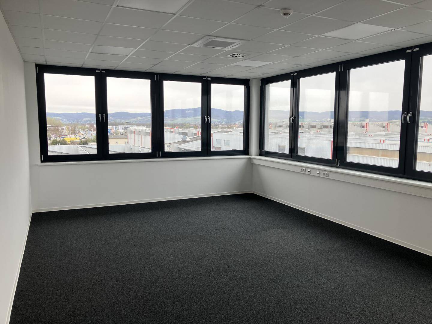 Geräumiges Eckbüro mit großen Fenstern, Teppichboden und weitem Ausblick.