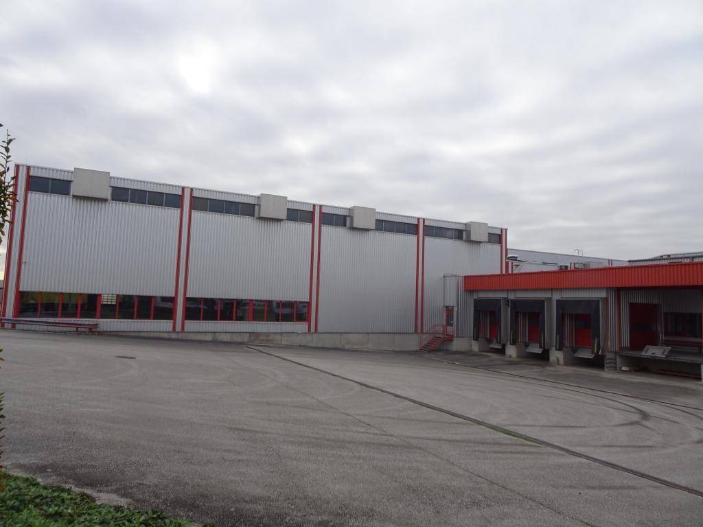 Gewerbegebäude mit Laderampen und einem großen Vorplatz unter bewölktem Himmel.