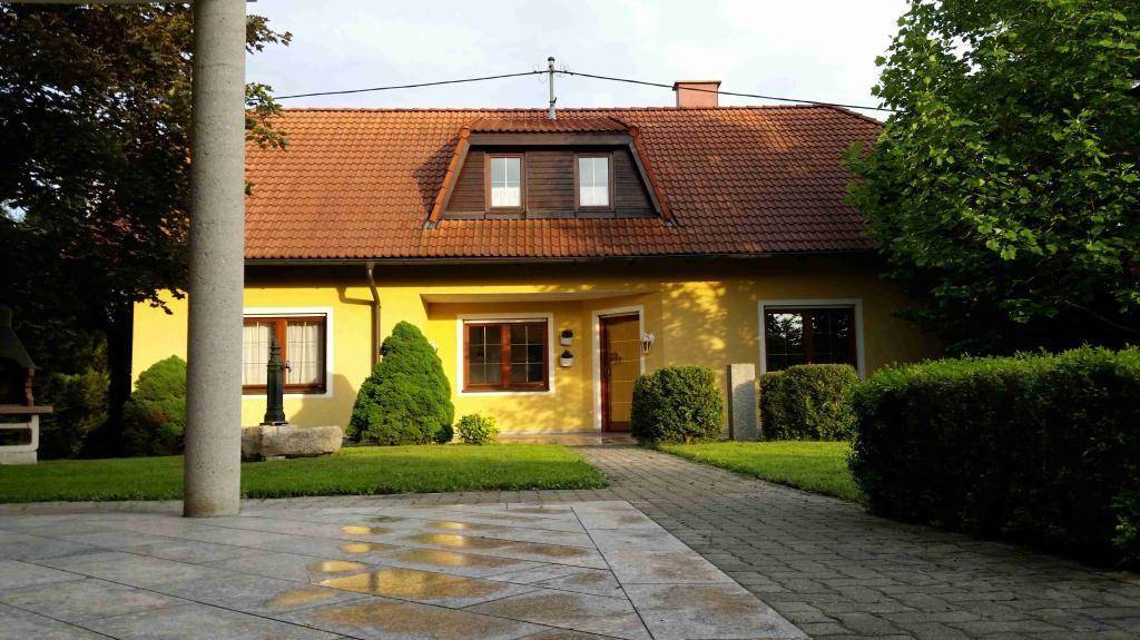 Vorderansicht des gelben Hauses mit gepflegtem Rasen und gepflastertem Zugang.