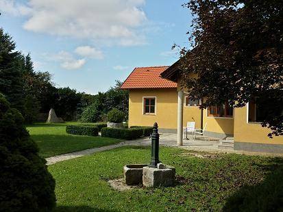 Weitläufiger Gartenbereich mit historischer Wasserpumpe und Blick auf das Haus.
