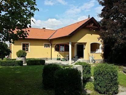 Hausansicht vom Garten aus mit überdachtem Eingangsbereich und gepflegter Rasenfläche.