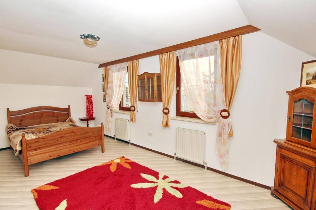 Helles Schlafzimmer mit Holzmöbeln, hellem Boden und Dachschrägen, gemütlich eingerichtet.