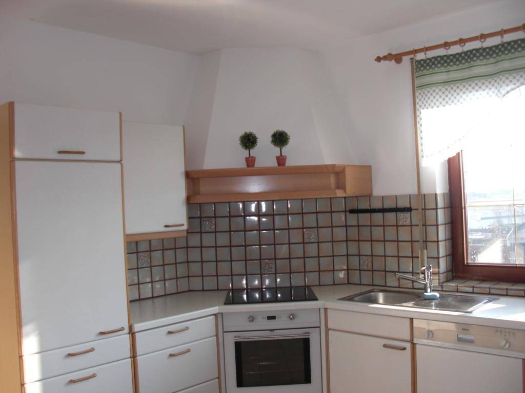 Funktionale Küche mit weißen Schränken, Fliesenrückwand und integriertem Backofen.
