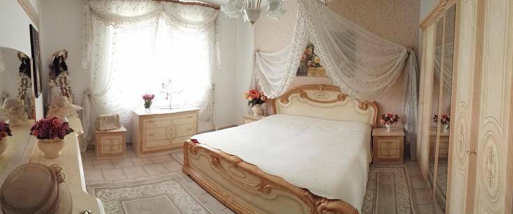 Elegantes Schlafzimmer mit Himmelbett, verzierten Möbeln und gemusterter Tapete.