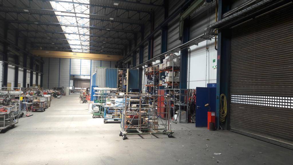 Weitläufige Industriehalle mit Rolltoren, Oberlichtern und verschiedenen Arbeitsbereichen, die aufgeräumt wirken.
