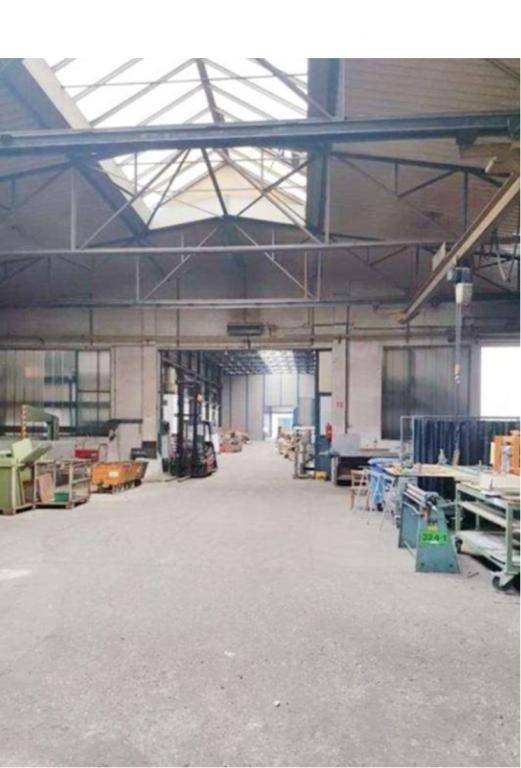 Geräumige Industriehalle mit hohen Decken, Oberlichtern und verschiedenen Arbeitsbereichen, die aufgeräumt wirken.