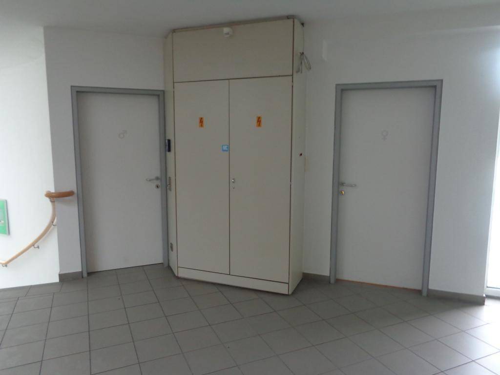 Funktionaler Bereich mit zwei Türen und einem großen Schrank, möglicherweise für Technik oder Lagerung, mit Fliesenboden.
