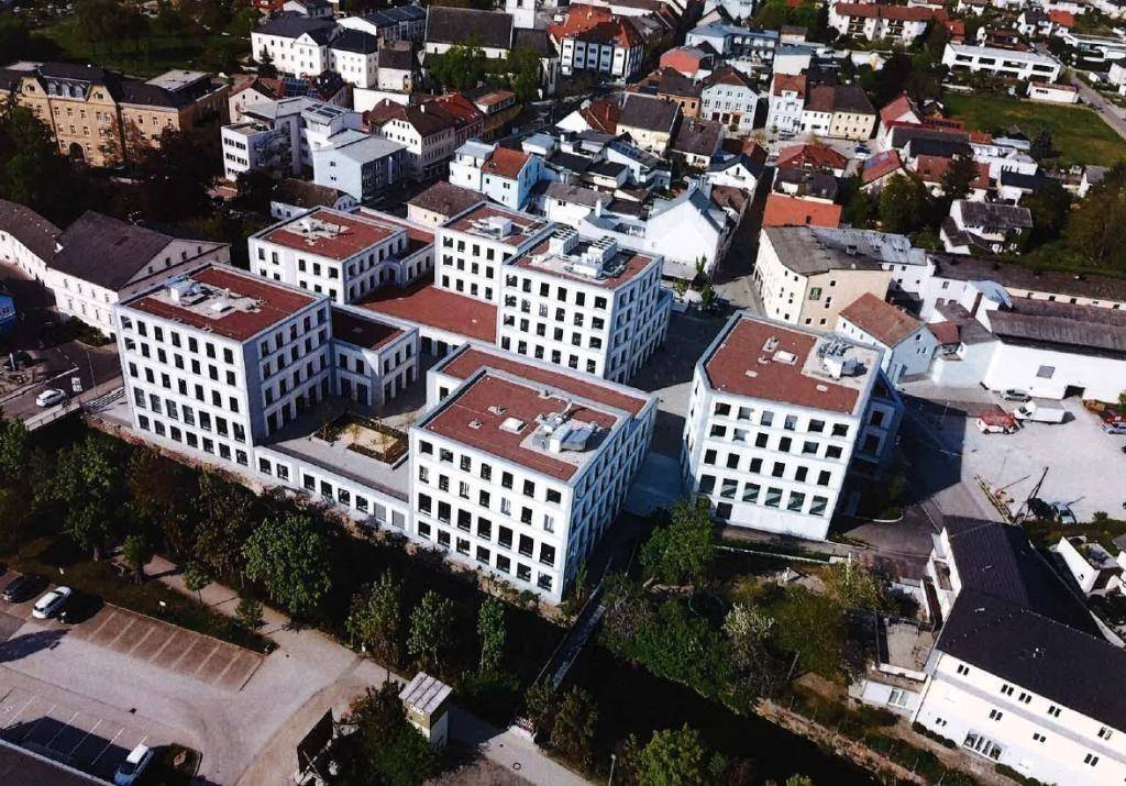 Eine weitere Luftaufnahme des modernen Gebäudekomplexes mit roten Dächern in einer städtischen Umgebung.