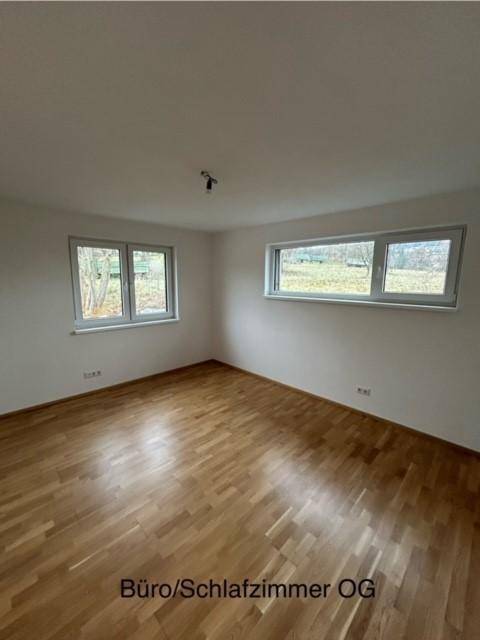 Helles Zimmer im Obergeschoss mit Holzparkettboden und zwei Fenstern, ideal als Büro oder Schlafzimmer.