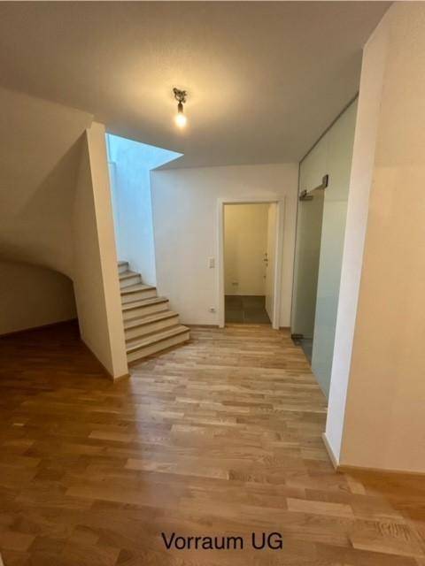 Geräumiger Vorraum im Untergeschoss mit Holzparkettboden und Treppe zum Obergeschoss.
