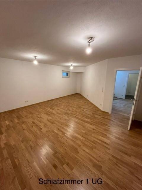 Helles Schlafzimmer im Untergeschoss mit Holzparkettboden und weiß gestrichenen Wänden.