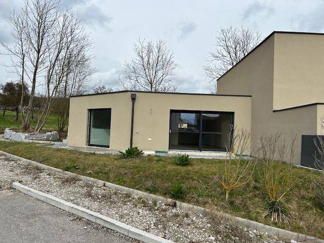 Ansicht des modernen Hauses von der Seite mit großen Fenstern und beiger Fassade.