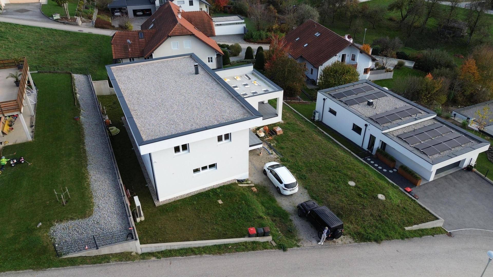 Neubau mit Flachdach und Photovoltaikanlage auf dem Nachbargebäude in ländlicher Umgebung.