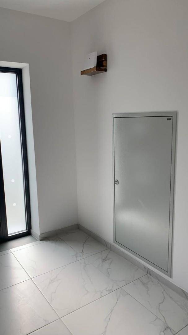 Heller Eingangsbereich mit modernen Fliesen und einer schlichten Wandverkleidung.