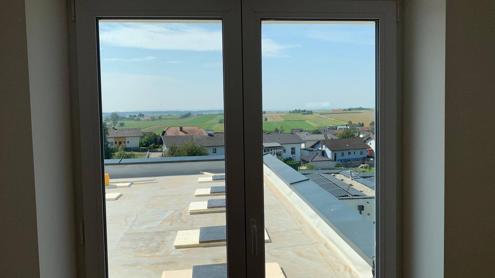 Heller Ausblick aus dem Fenster auf die ländliche Umgebung und die Baustelle des Flachdachs.