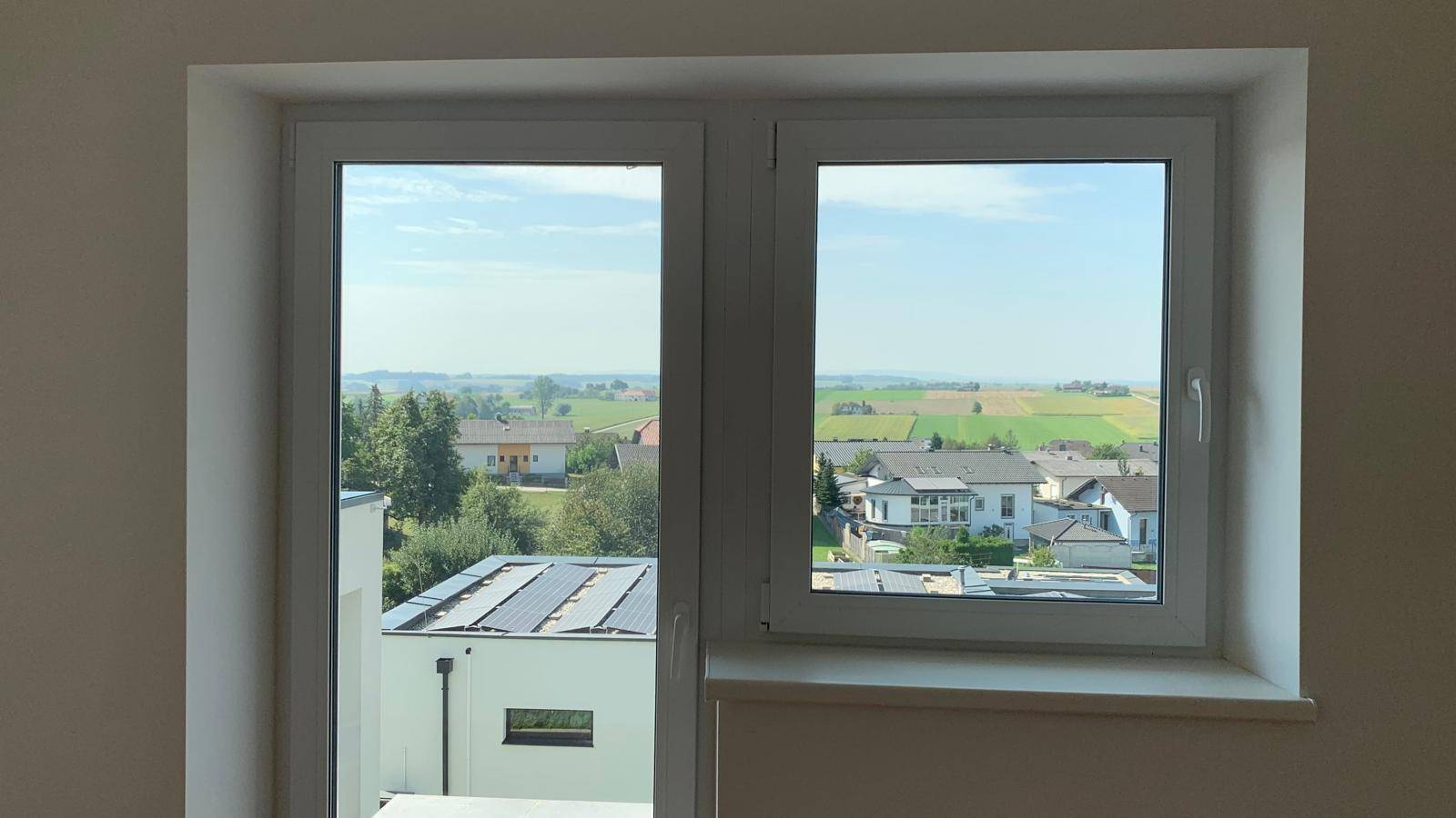 Weitblick aus dem Fenster über die ländliche Umgebung mit Feldern und Häusern.