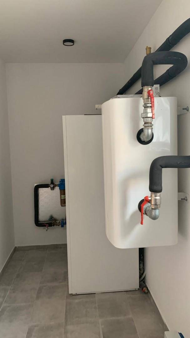 Technikraum mit Warmwasserspeicher und sichtbaren Rohrleitungen für die Haustechnik.