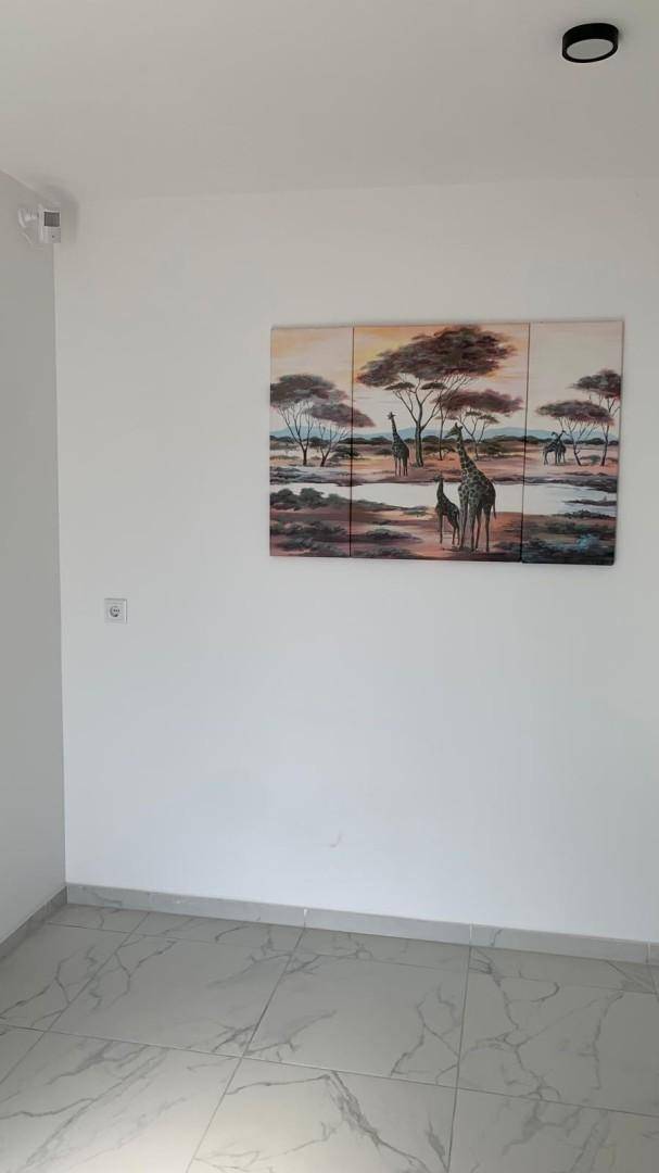 Heller Raum mit Fliesenboden und einem Wandbild mit afrikanischem Savannenmotiv.