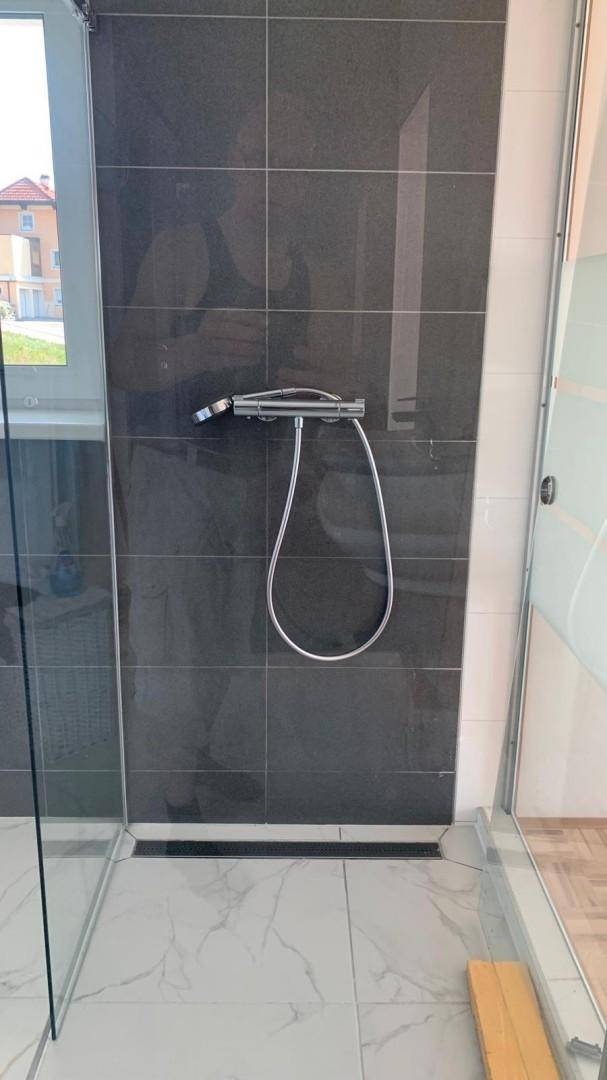 Moderne Duschkabine mit dunklen Fliesen und Glasabtrennung im Badezimmer.