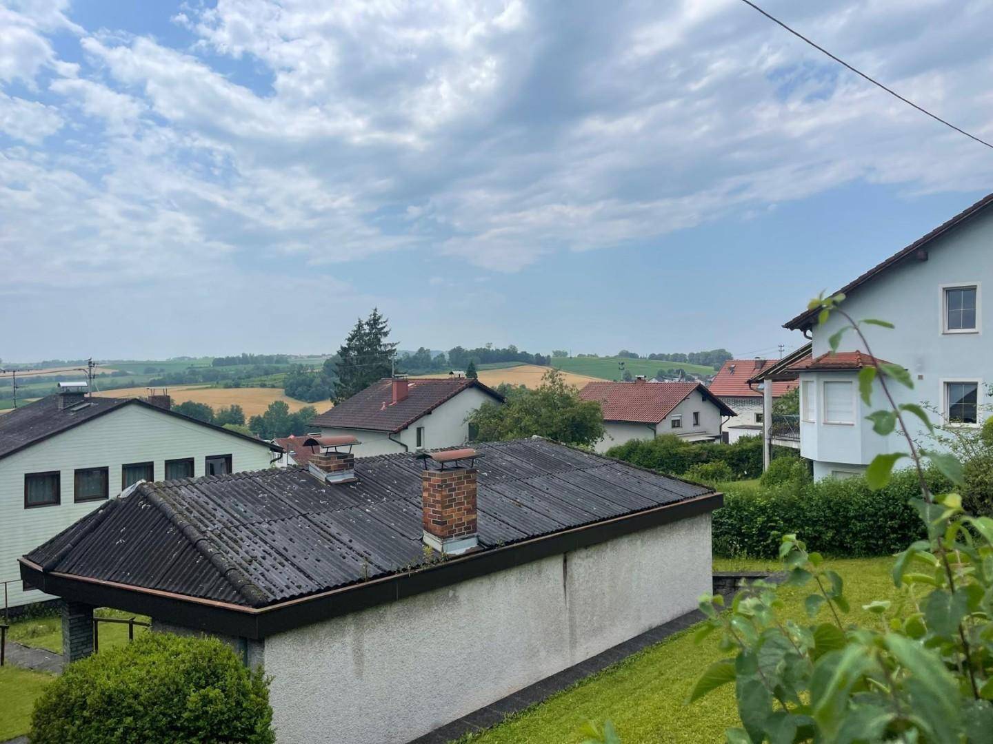 Gartenansicht mit Rasenfläche und weitem Blick über die Felder unter bewölktem Himmel.