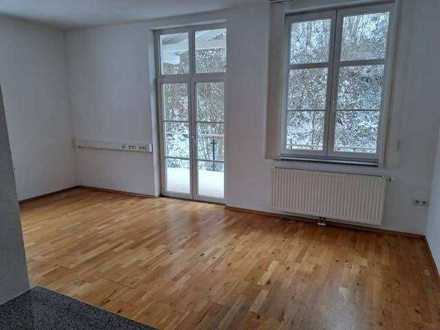 Heller Raum mit großen Fenstern und Holzboden, bietet einen weiten Blick auf die verschneite Natur.