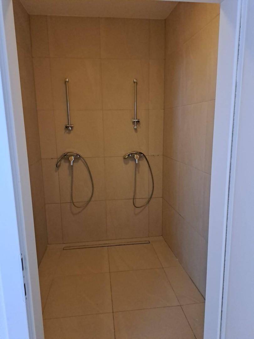 Modern geflieste Duschkabine mit zwei Duschköpfen und minimalistischem Design.