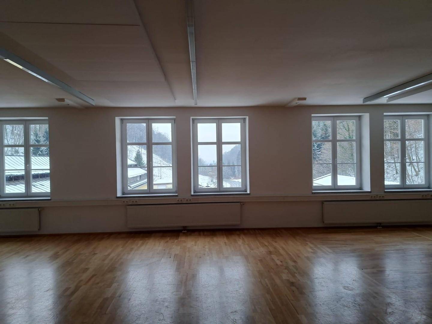 Heller Raum mit mehreren Fenstern, die einen weiten Blick auf die verschneite Landschaft bieten.