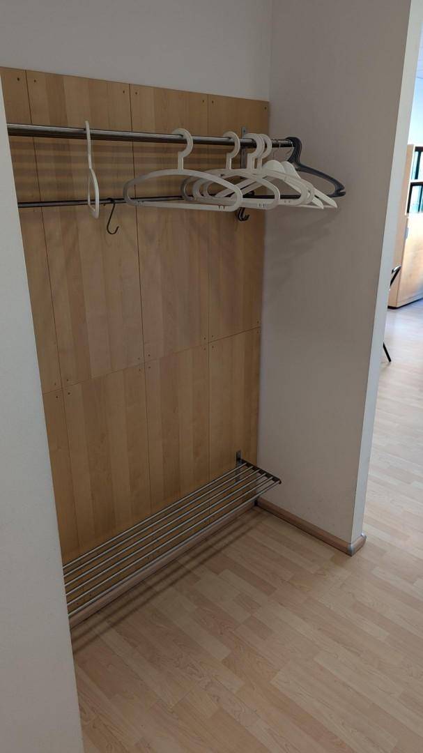 Flur mit Garderobe, Kleiderbügeln und einem Regal, ausgestattet mit hellem Holzfußboden.