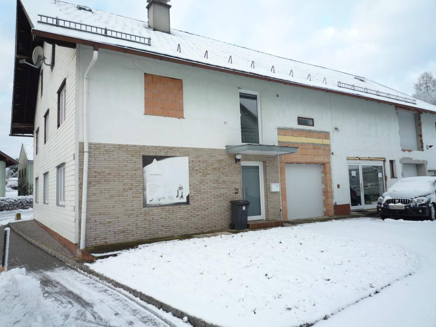 Vorderansicht des Wohnhauses im Winter mit verschneitem Vorgarten und Garagentor.