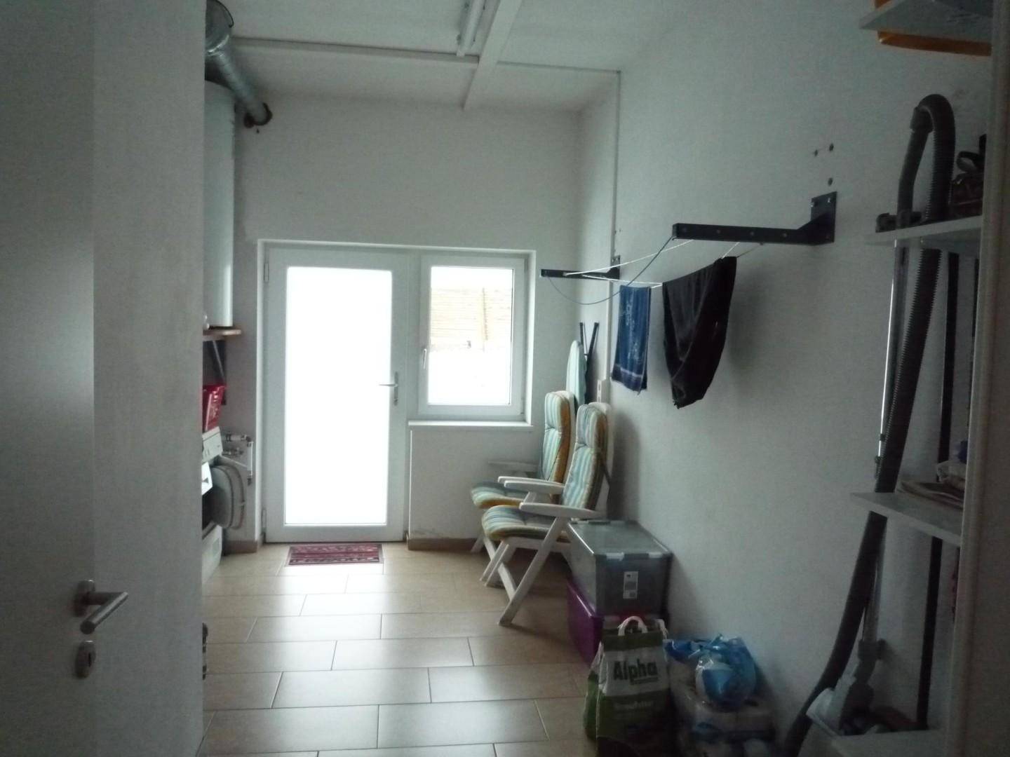 Hauswirtschaftsraum mit Fliesenboden, Waschbereich und Zugang zum Garten.