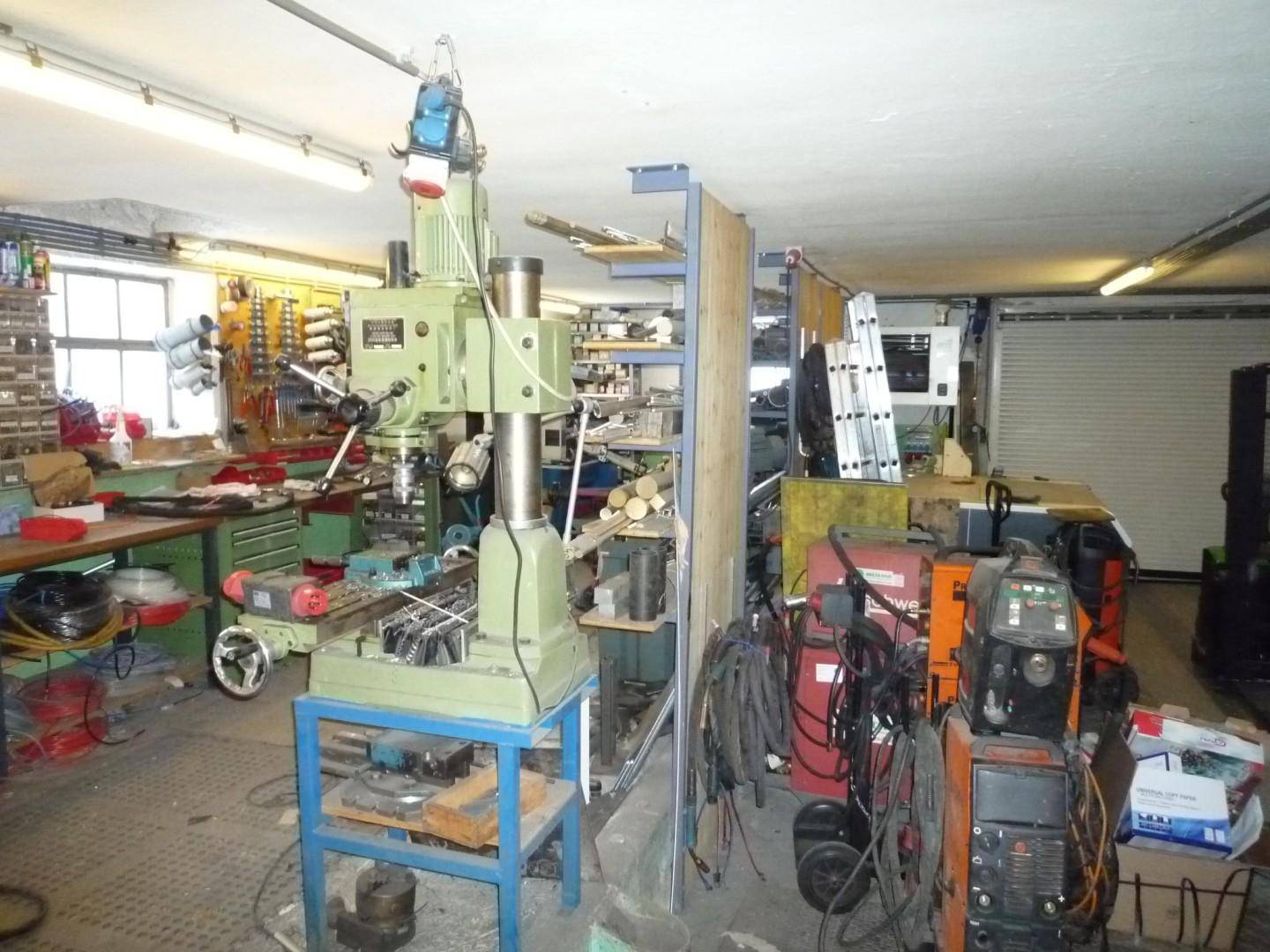 Geräumige Werkstatt mit verschiedenen Maschinen, Werkzeugen und Lagerregalen.