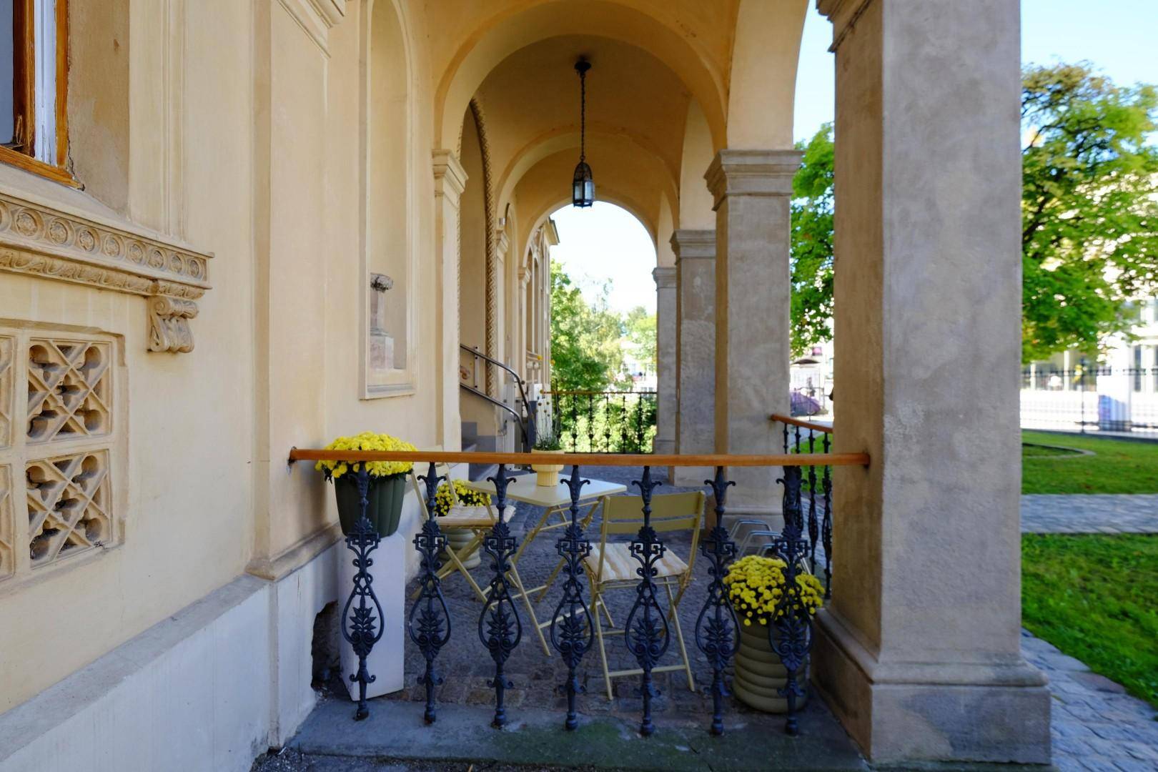 Gemütlicher überdachter Sitzbereich im Freien unter den Bögen der Villa mit Blumen.