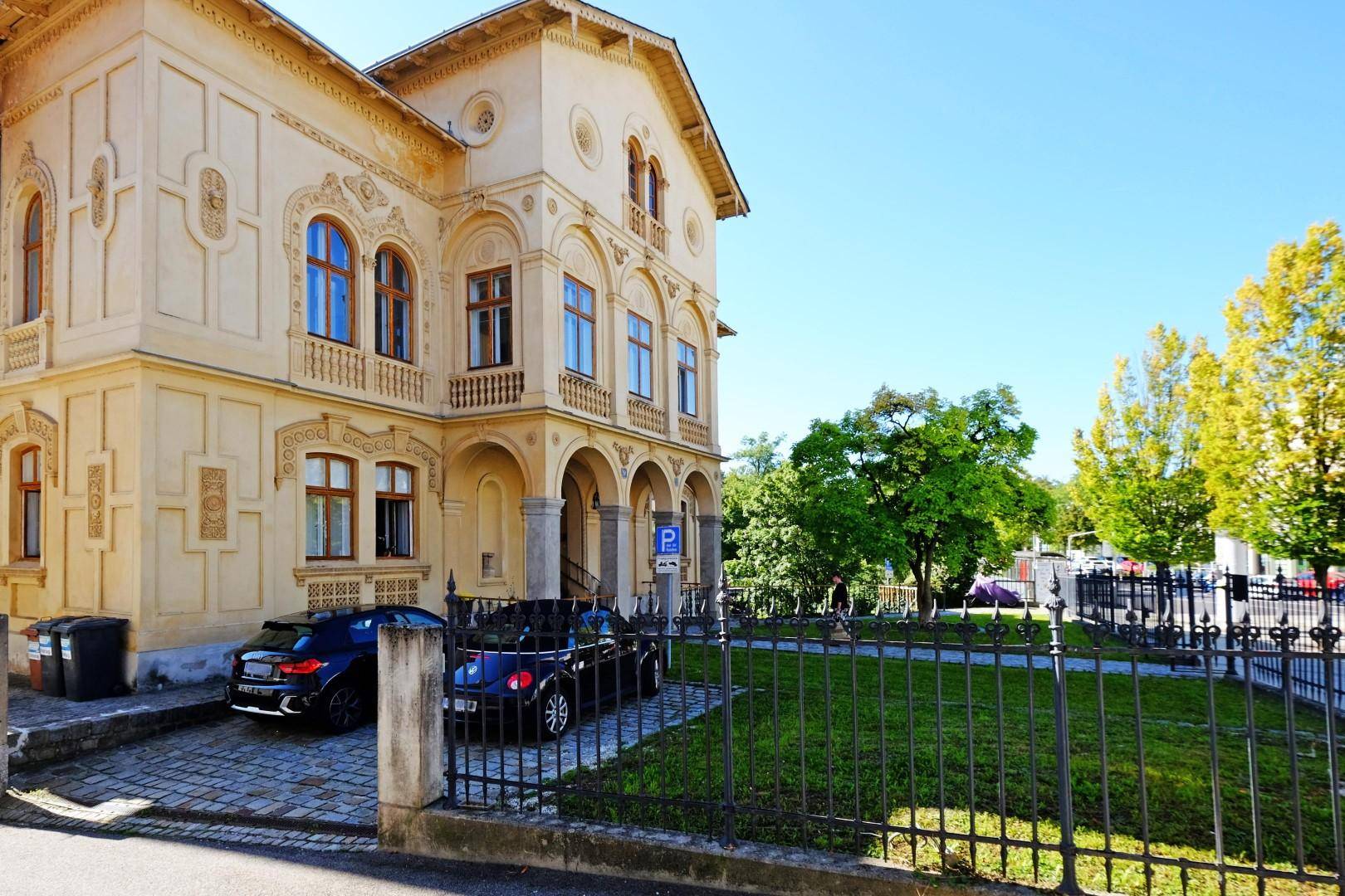 Historische Villa mit gepflegtem Vorgarten und Parkmöglichkeiten vor dem Gebäude.